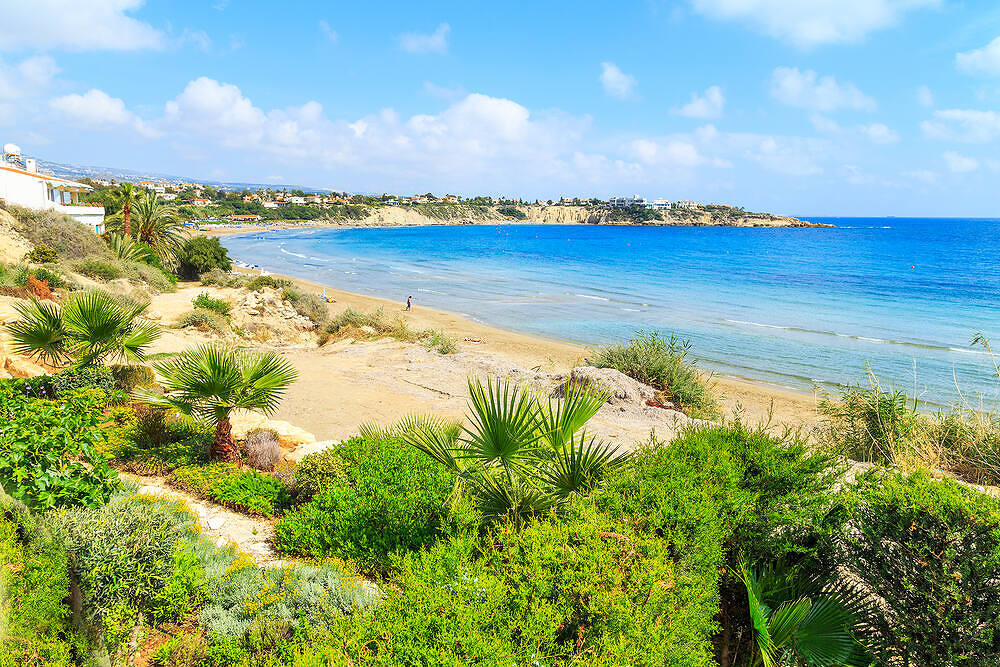 Scenic Cyprus coastline with crystal-clear blue water, sandy beach, and Mediterranean vegetation, perfect for rehabilitation