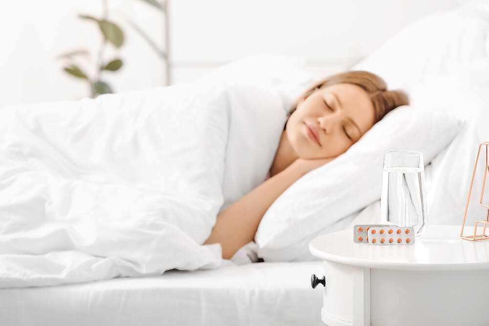 Woman resting peacefully in bed during home alcohol detox, with medication and water on bedside table