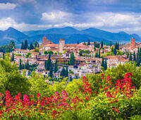 Picturesque view of a traditional Spanish village nestled in mountains, with colorful flowers in foreground, symbolizing hope and new beginnings in addiction recovery