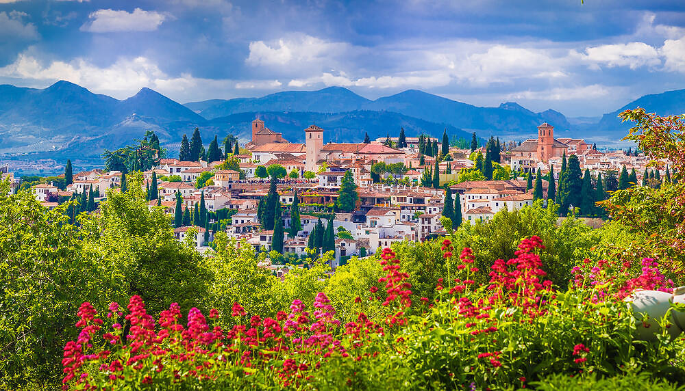 Picturesque view of a traditional Spanish village nestled in mountains, with colorful flowers in foreground, symbolizing hope and new beginnings in addiction recovery