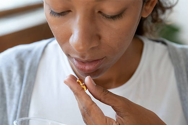 Close-up of a young woman about to take an Adderall pill, illustrating the personal struggle with prescription stimulant addiction