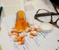 Spilled Adderall pills from prescription bottle next to glasses and notepad, illustrating addiction and treatment