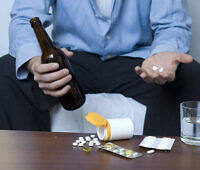 Man holding beer bottle and pills, depicting risky combination of alcohol and medications like naproxen