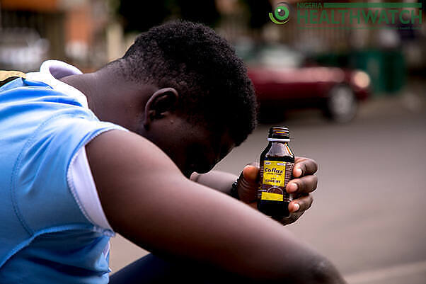 Young man holding a bottle of codeine cough syrup, illustrating the issue of codeine addiction among youth