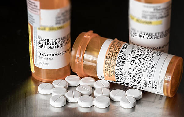 Prescription bottles of Oxycodone with white pills spilled out, illustrating the potential for abuse of dangerous prescription drugs