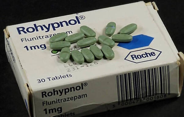 Box of Rohypnol (Flunitrazepam) 1mg tablets manufactured by Roche, with green oval pills scattered on top