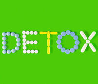 Colorful arrangement of pills spelling "DETOX" on a green background, symbolizing drug detoxification.