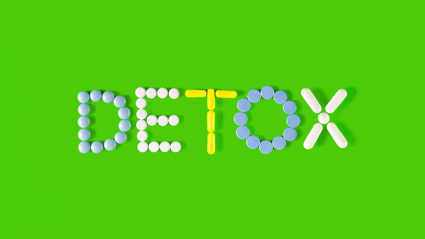 Colorful arrangement of pills spelling "DETOX" on a green background, symbolizing drug detoxification.