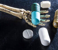 Skeletal hand holding colorful pills and capsules, illustrating the dangers of drug abuse and addiction