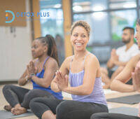 Women doing yoga in recovery laughing with each other surrounded by yoga group sitting on the floor