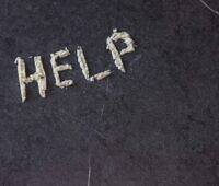 The word 'HELP' spelled out with white powder on a dark surface, illustrating the cry for assistance often associated with cocaine addiction