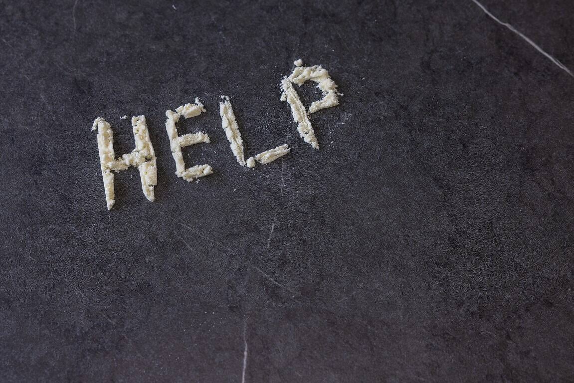 The word 'HELP' spelled out with white powder on a dark surface, illustrating the cry for assistance often associated with cocaine addiction