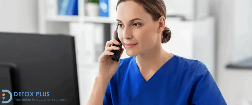 Female doctor in blue scrubs on the phone looking at a computer