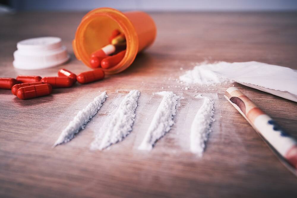 Cocaine laid out on a table with a bottle of antibiotics spread across a table