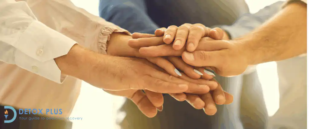rehab group putting hands together supporting eachother in treatment