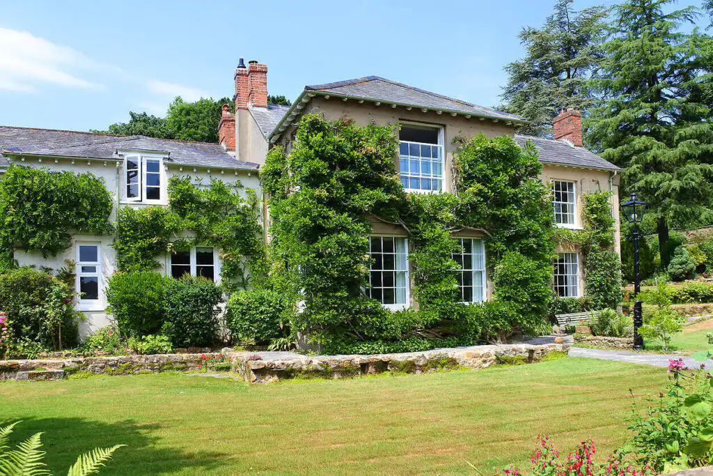 Historic Manor House Rehab Center in Nottinghamshire Charming English country house with ivy-covered walls, surrounded by lush gardens, ideal for alcohol rehabilitation in England|Smiling middle-aged woman with red hair in counseling session with therapist, sitting in bright room, depicting supportive environment for addiction recovery