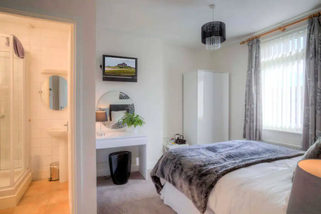Comfortable Private Room in Alcohol Rehab Center Nottinghamshire Cozy bedroom in Nottinghamshire alcohol rehabilitation facility featuring en-suite bathroom, TV, dressing table, and large windows, offering a welcoming environment for recovery