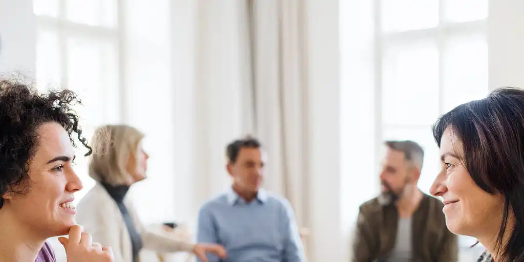 Diverse group of adults engaged in a supportive therapy session for addiction recovery, smiling and interacting in a bright, welcoming room|Vibrant Northamptonshire landscape with a field of yellow rapeseed flowers dotted with red poppies, stretching to the horizon under a clear blue sky, symbolizing hope and renewal in addiction treatment|A male counselor in a suit meeting with an older female patient in a professional office setting, discussing addiction treatment options|Collage of a luxurious rehab center featuring an elegant white building exterior, a cozy bedroom with plush bedding, and a dining area with fresh flowers and fruit, showcasing high-end addiction treatment facilities|Collage of a Northamptonshire rehab center featuring a luxurious brick building exterior, modern gym equipment, and an indoor swimming pool for holistic recovery