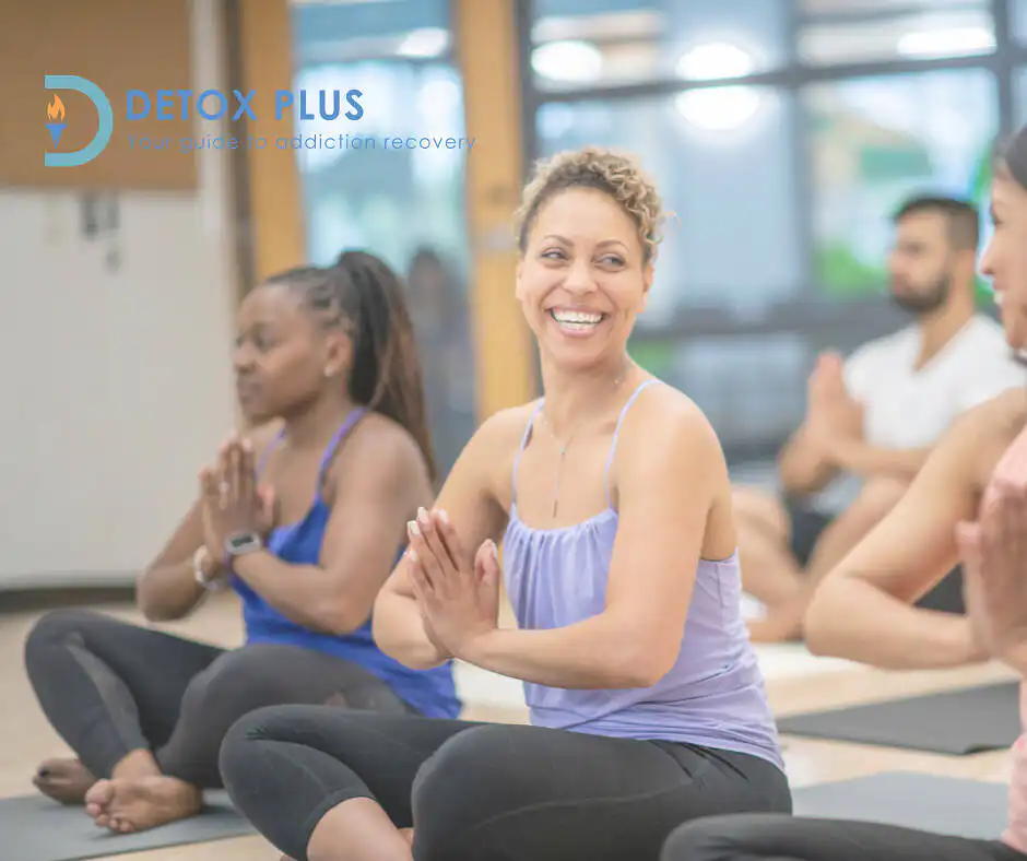 Women doing yoga in recovery laughing with each other surrounded by yoga group sitting on the floor|Two women outside laughing during a recovery exercise